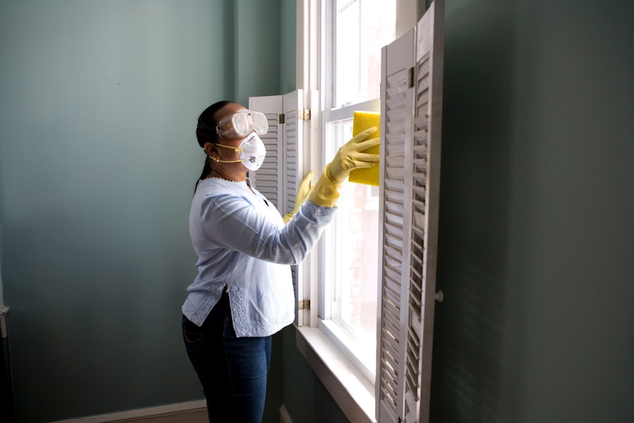 A cleaner in gloves and protective gear detailing a window